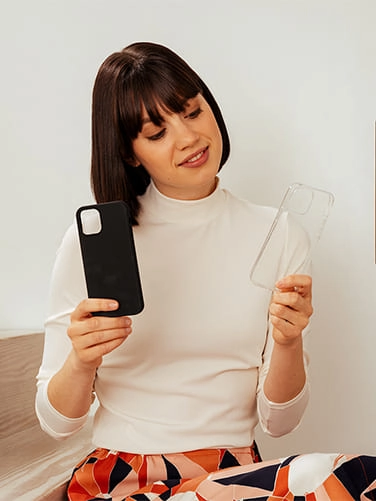Mujer sosteniendo una funda de Silicona y una funda de cuero en sus manos.