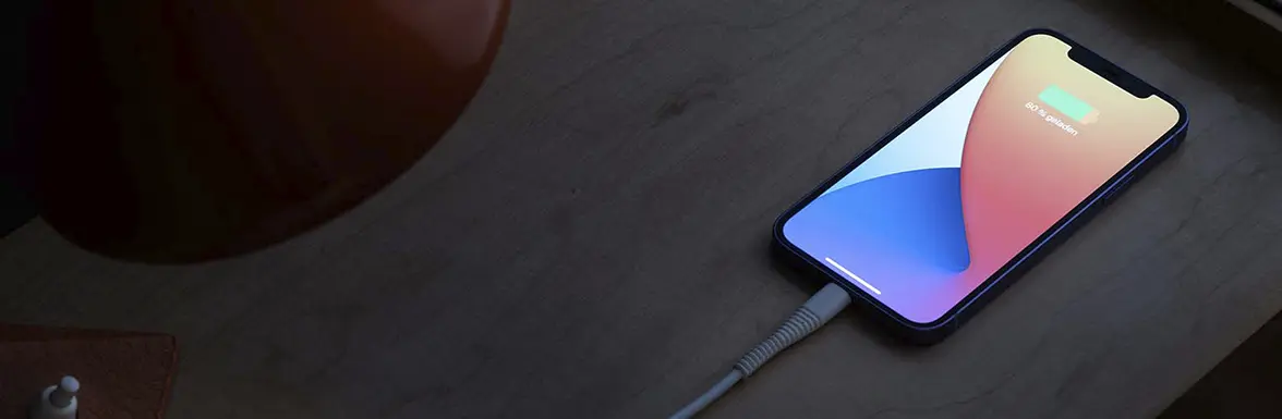 Un teléfono móvil se carga por la noche en la mesilla por medio de un cable