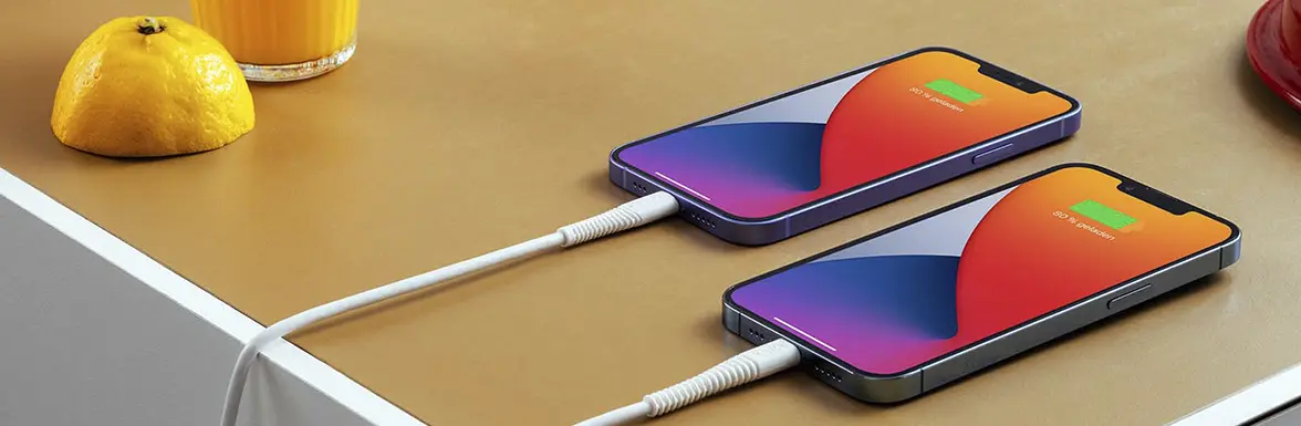 Sobre la mesa hay dos iPhones que se están cargando.