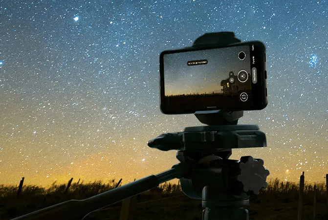 El teléfono móvil se fija al trípode y se apunta hacia el cielo nocturno.
