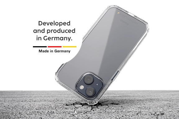 Un smartphone está en una funda de móvil Hama y cae con la esquina superior sobre el duro asfalto; pero el asfalto se rompe, el smartphone permanece intacto. En un botón blanco se lee «Desarrollado y producido en Alemania» en letras negras.