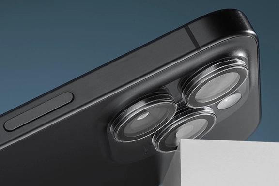 La parte trasera de un smartphone choca contra un borde afilado con la cámara, pero esto no es un problema, ya que las cámaras están protegidas por el protector de cámara «Cam Protect» de Hama con 3 lentes individuales.