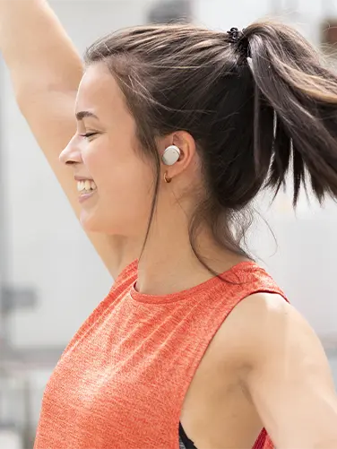 La persona lleva los auténticos auriculares inalámbricos en la oreja.