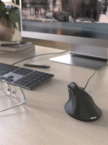 La souris ergonomique est posée sur le bureau.