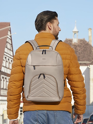 Un joven pasea por la ciudad con la mochila para portátil «Premium Lightweight» de Hama a la espalda