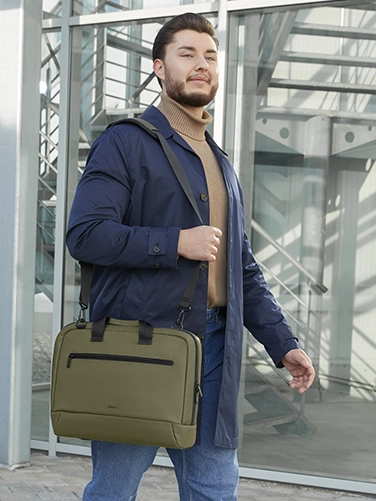 Un hombre de negocios se echa al hombro la bolsa para portátil "ultraligera" de Hama de camino a la próxima reunión