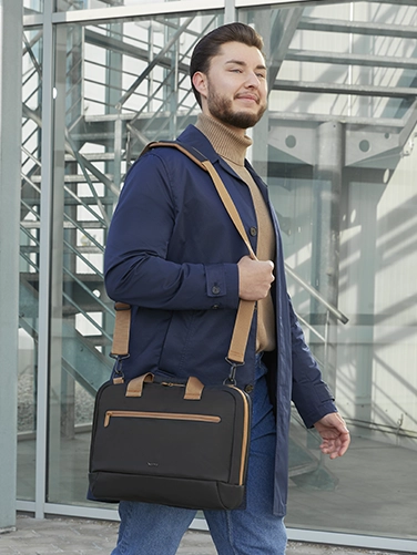 Un hombre de negocios se echa al hombro la bolsa para portátil "ultraligera" de Hama de camino a la próxima reunión